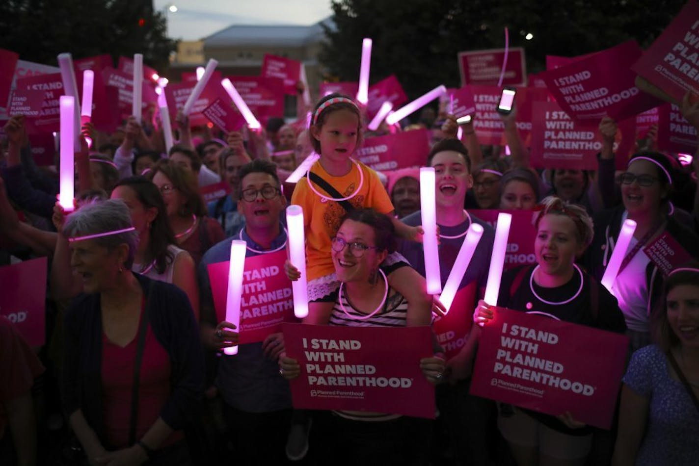 Carissa Coudray and her daughter, Olive Middleton, were among the crowd chanting at the rally in front of Planned Parenthood of Minnesota's headquarters Wednesday at dusk.