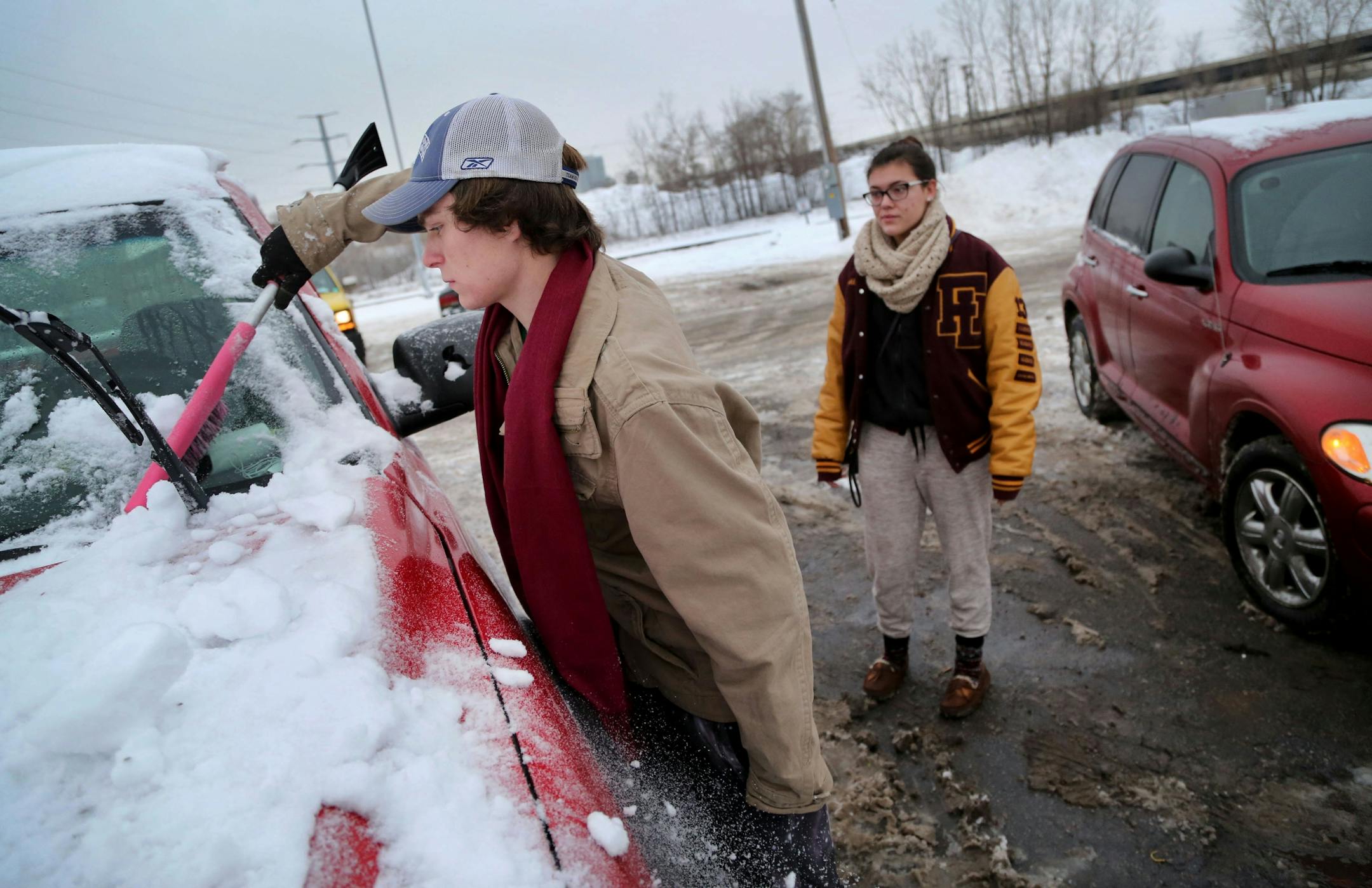 Minneapolis resident Coltin Paddock cleans snowed off his newly recovered truck as his girlfriend Kelli Lukkonene stands next to her Chrystler Crusiser outside the city of Minneapolis auto impound lot Wednesday, Dec. 30, 2015, in Minneapolis, MN. The couple had both their vehicles towed, including Paddock's 2002 Chevy Silverado truck, from Como SE Avenue and paid $276 to get them out. "I'm about to go broke," said Paddock, an electrician who also plows to make extra money."