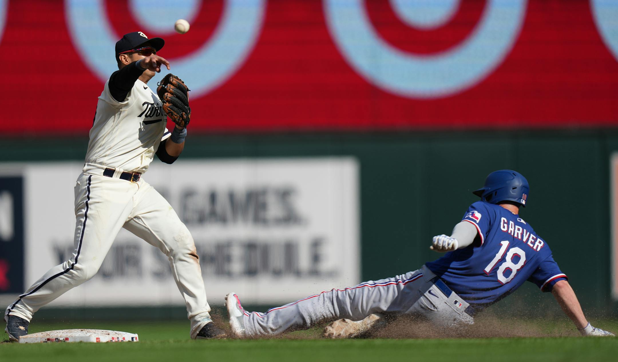 Minnesota Twins second baseman Jorge Polanco (11) turns a double plays as Texas Rangers catcher Mitch Garver (18) slides into second base in the 10th inning in Minneapolis, Minn., on Monday, Aug. 28, 2023. Texas Rangers take on the Minnesota Twins at Target Field.] RICHARD TSONG-TAATARII • richard.tsong-taatarii @startribune.com