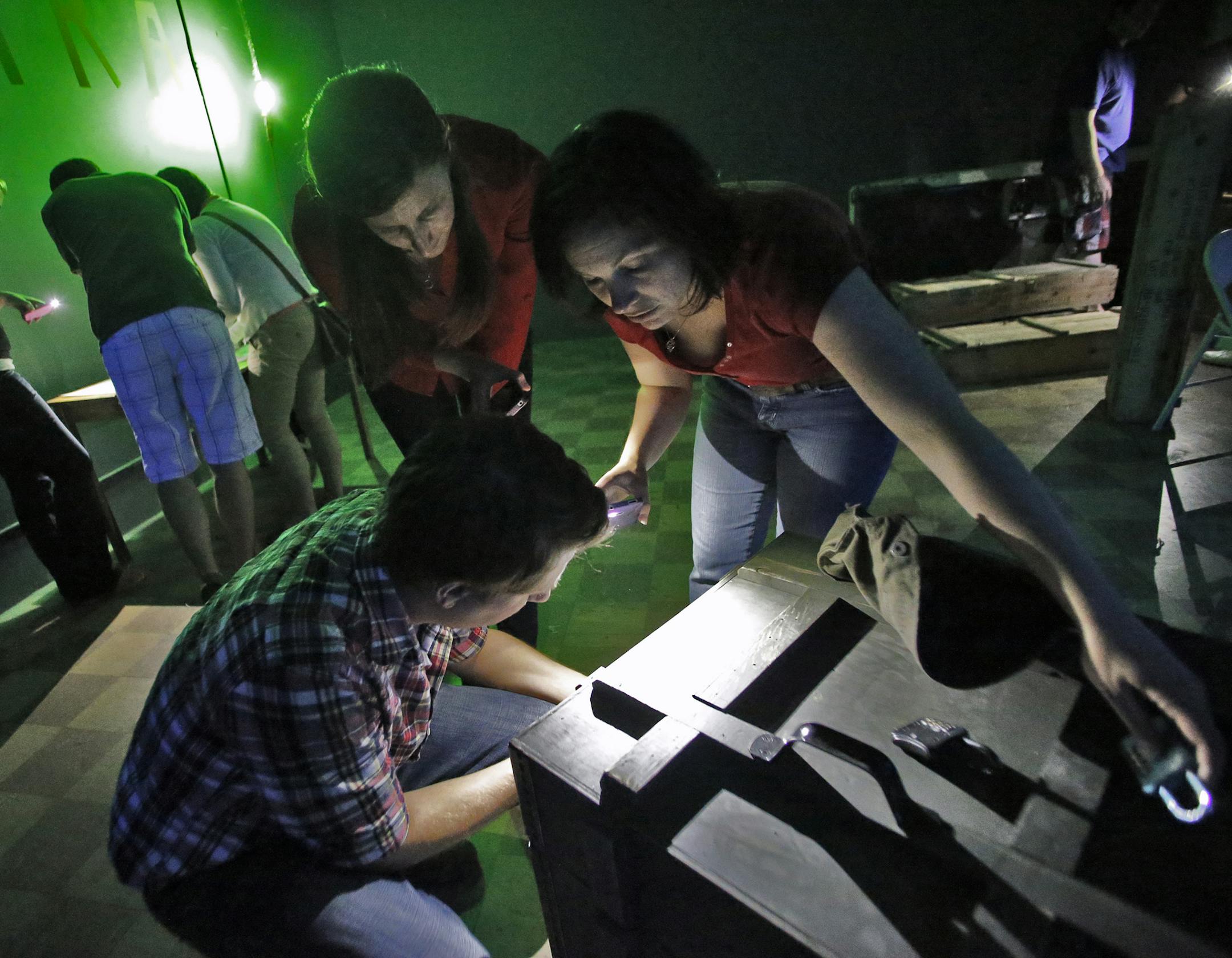 A group works on the various clues presented to them in an effort to find passage out of the riddle room. Some attempt to unlock a chest in foreground while others seek clues from a map at left. ] The Riddle Room Bunker in Minneapolis. (MARLIN LEVISON/STARTRIBUNE(mlevison@startribune.com)
