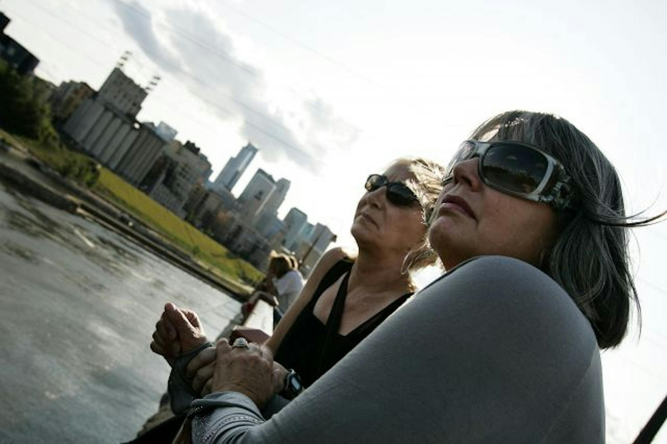 On the 2nd anniversary of the I-35W bridge collapse, at 6:05 p.m. Minneapolis neighbors Alison Howland, left, and Nancy Hovanes, stand on the Stone Arch Bridge and look towards the new I-35W bridge.