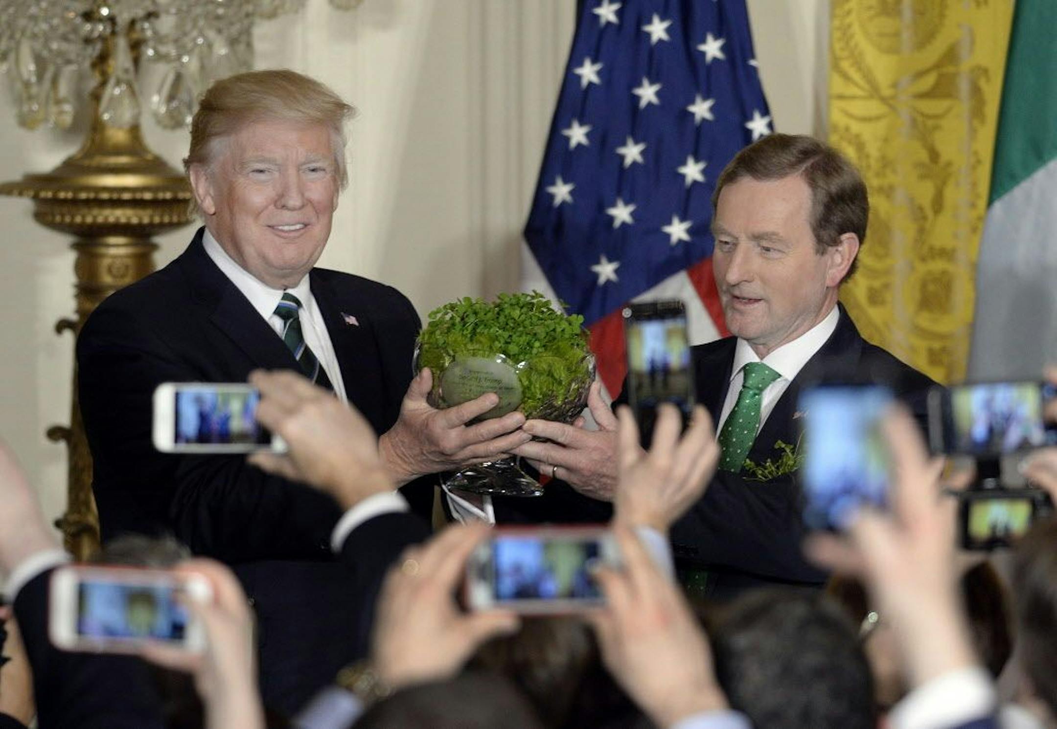 U.S. President Donald J. Trump, left, accepts a bowl of shamrocks from Taoiseach of Ireland Enda Kenny on March 16, 2017 during a reception in the East Room of the White House in Washington, D.C.