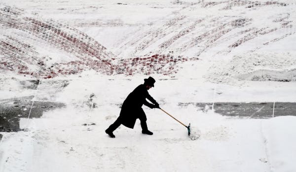 St. Paul Hotel doorman Tyson Heinz struggled to keep the hotel driveway clear as snow continued Sunday morning.