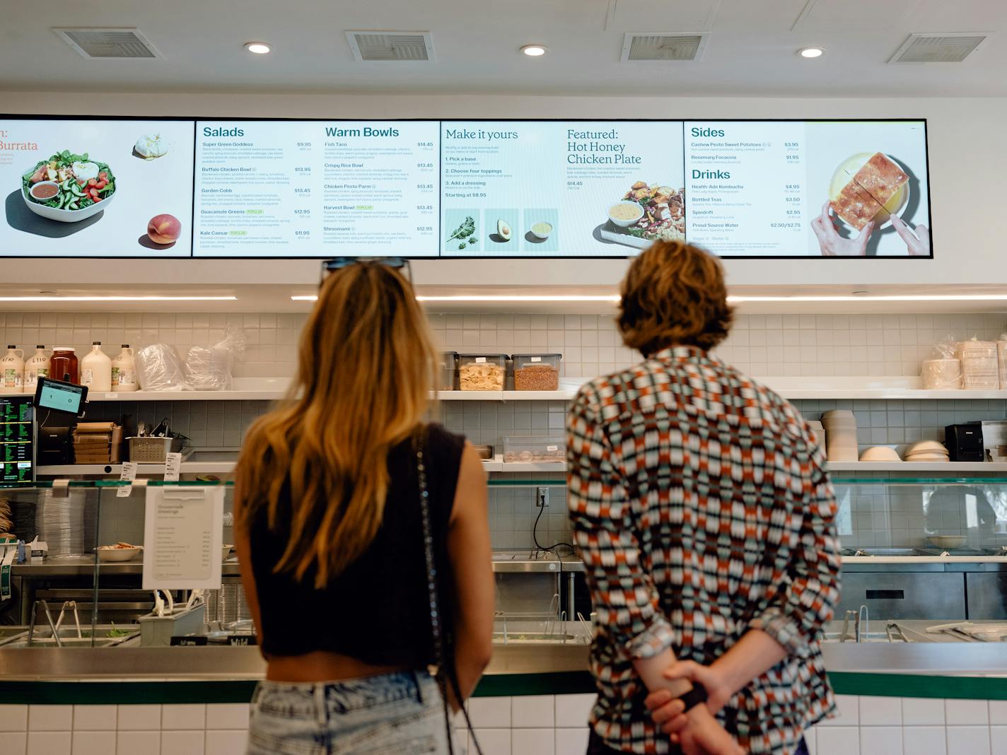 Customers look over the menu at a Sweetgreen restaurant in Santa Monica, Calif., on June 14, 2021. Sweetgreen, which has 129 restaurants across more than a dozen states, is among the businesses that have been obsessively tracking coronavirus case numbers. (Rozette Rago/The New York Times)