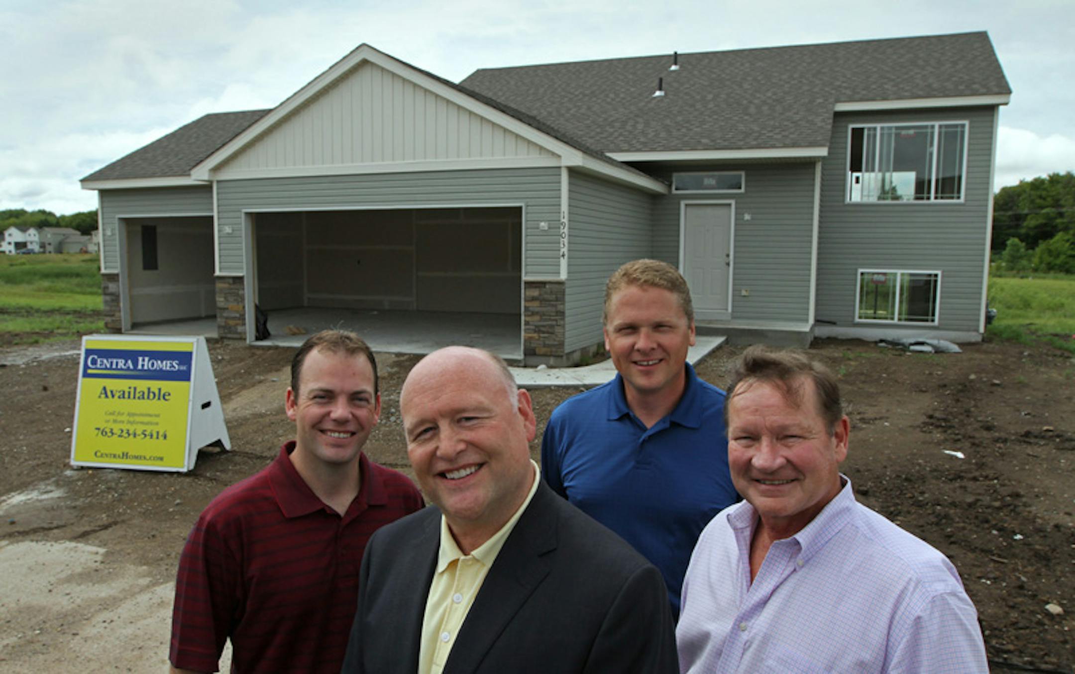 From left, Chris Wold, a Meridian Land Co. VP; Glenn McCabe, Meridian executive VP, Dale Wills of Centra Homes, and Rick Murray, Meridian senior VP, in front of a house that Centra is building on Quincy Street in Elk River.