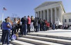 Visitors wait on the plaza of the Supreme Court in Washington, Tuesday, March 29, 2016, as the justices split 4-4 in a case that considered whether pu