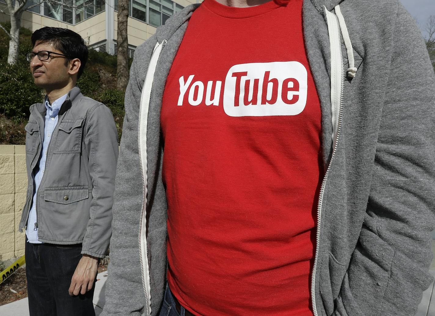 People wait to be escorted into a YouTube office building in San Bruno, Calif., Wednesday, April 4, 2018. A woman suspected of shooting three people at YouTube headquarters before killing herself was furious with the company because it had stopped paying her for videos she posted on the platform, her father said Tuesday, April 3, 2018. (AP Photo/Jeff Chiu)