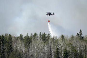 Crews from the Minnesota Army National Guard use Blackhawk helicopters to scoop water from Indian Lake as they worked to douse the Camp House fire Tue