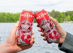 Toasting by a lake with two bright red cans of Strawberry Fields sour ale from Indeed Brewing.