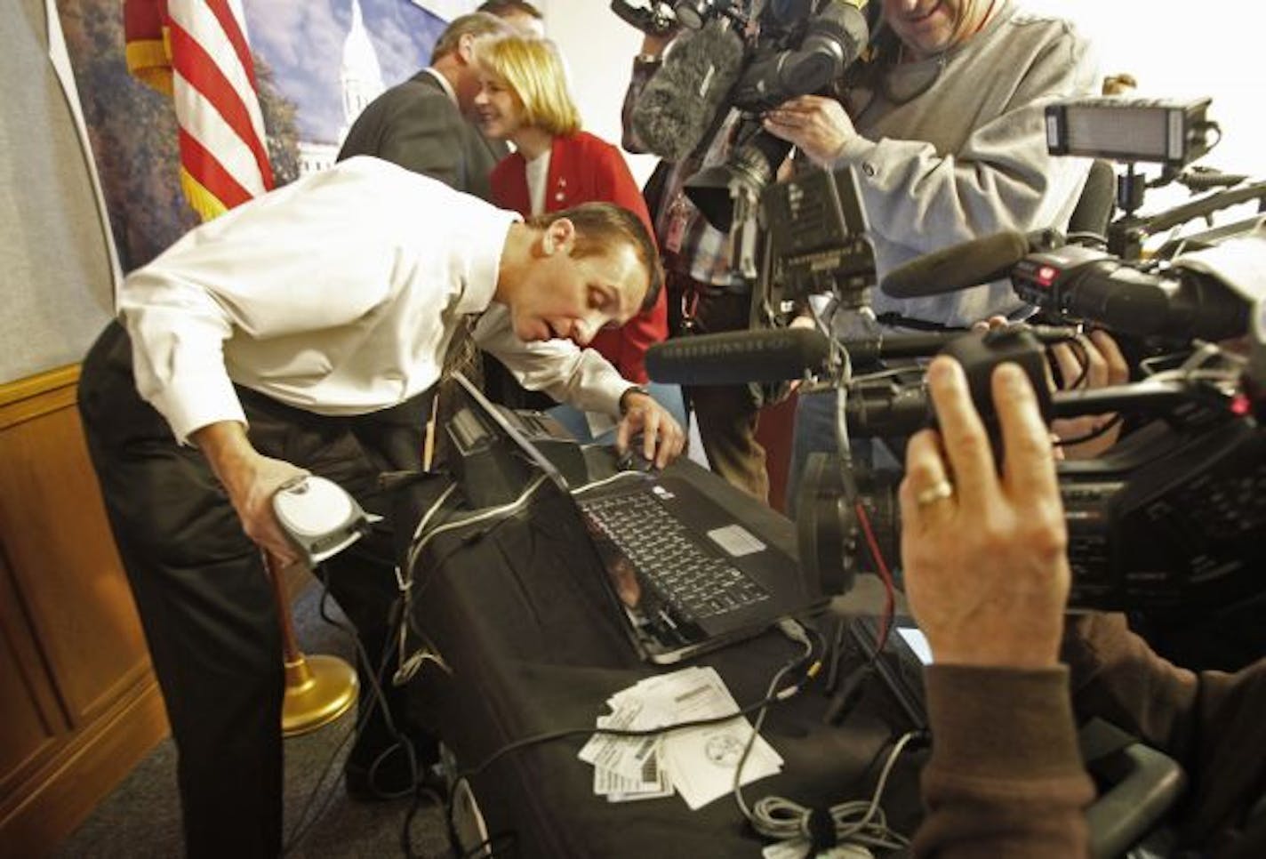 Scott Kullman of the Datacard Group demonstrated a voter ID verification machine to media members Wednesday at the State Capitol. To his left was Rep. Mary Kiffmeyer, who is sponsoring a voter ID bill in the House.