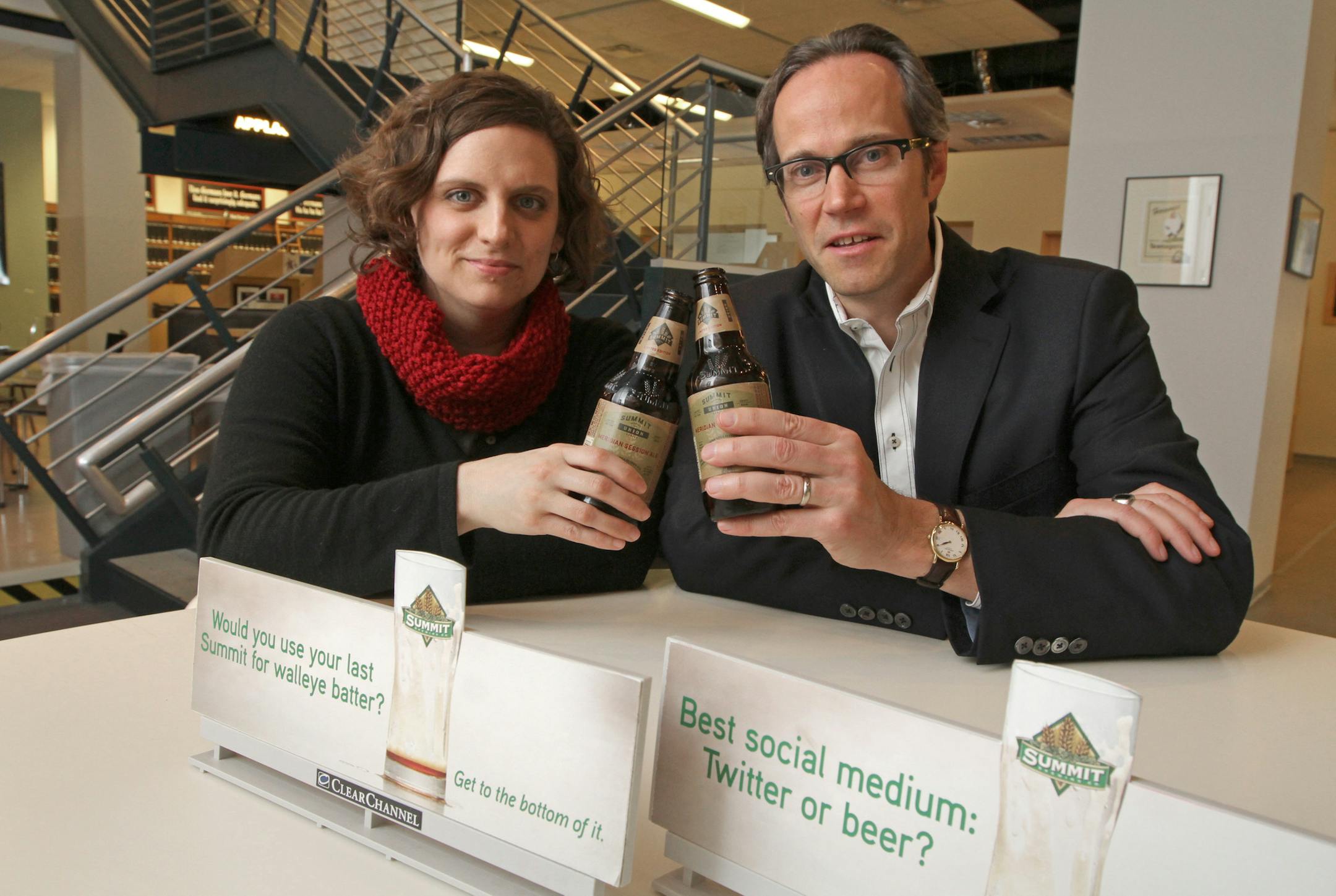 (left to right) Carey Matthews, Summit Brewing Marketing Coordinator and Doug deGrood, GdB creative director were photographed at the GdB offices in downtown Minneapolis on 4/23/13 with several miniature billboards advertising Summit Brewing. The Minneapolis ad agency DgB has helped Summit Brewing increase sales by 8 to 10 percent in each of the last five years with the help of an empty glass of beer and the slogan "Get to the Bottom of it" and a ubiquitous question along the lines of "If facebo