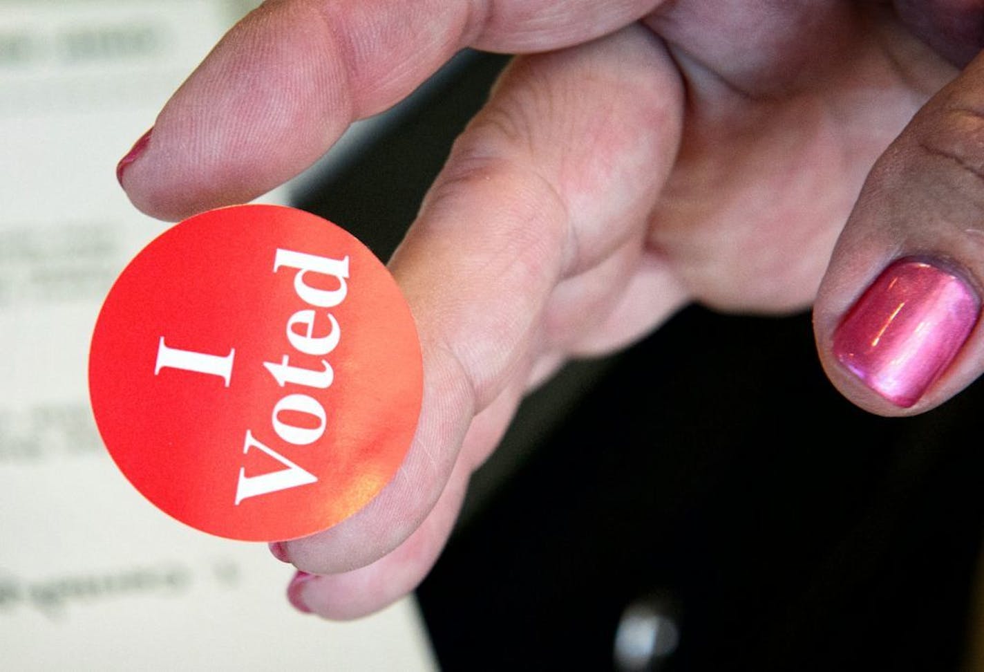 A poll worker offered an I Voted sticker to a voter in Apple Valley in 2014.