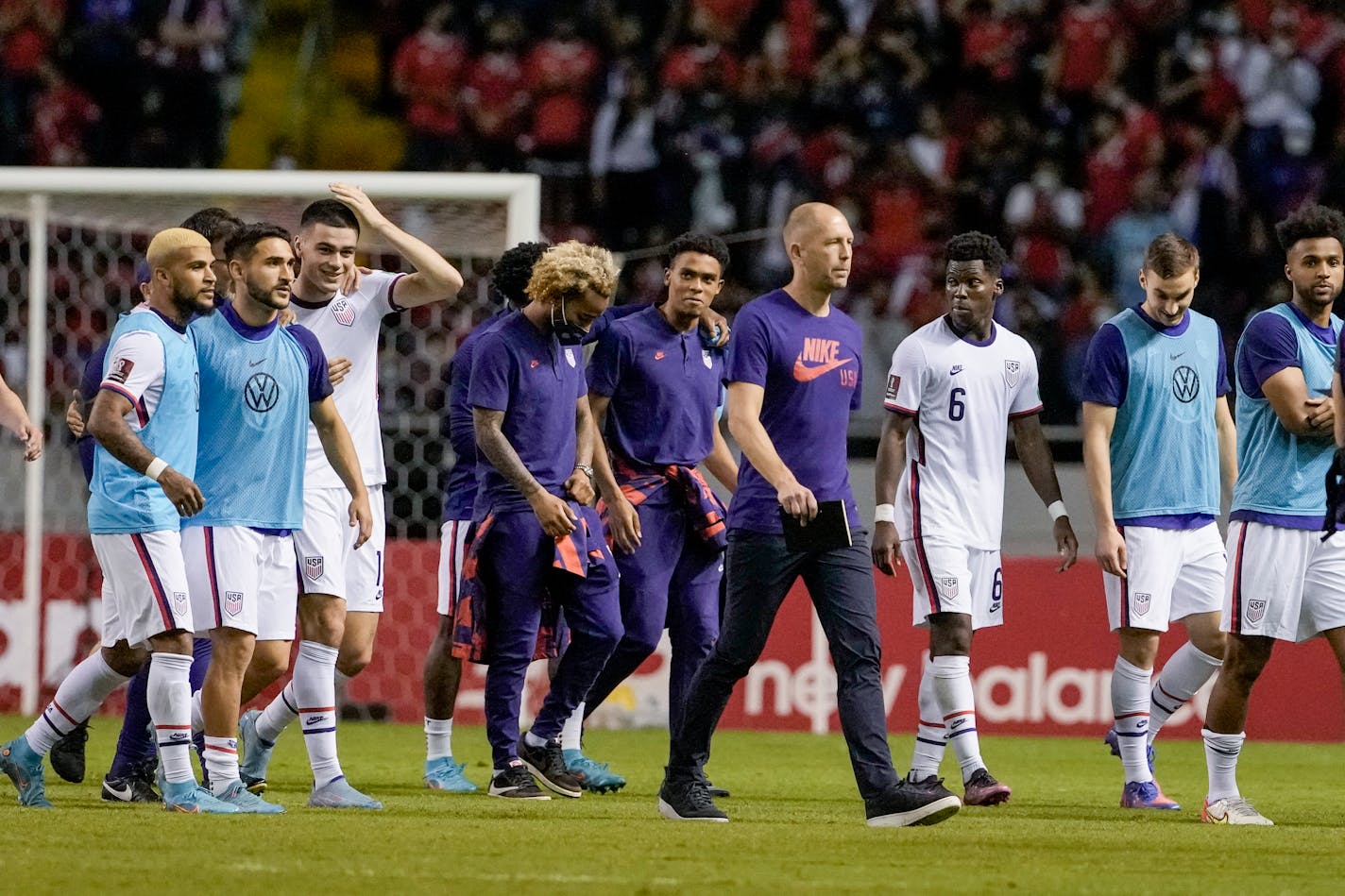 United States' coach Gregg Berhalter, center, and his team's players leave the pitch after losing 2-0 to Costa Rica yet still qualifying for the World Cup