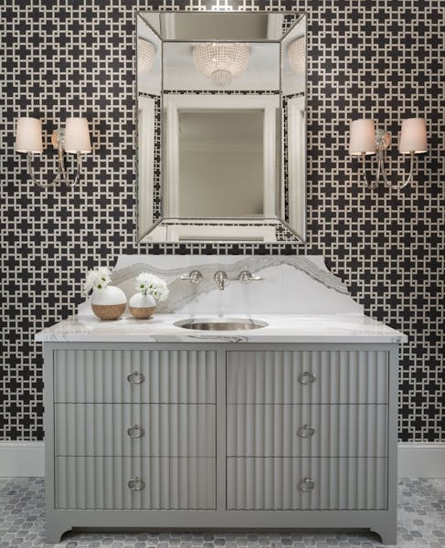 The powder room makes a bold statement with geometric patterned wallpaper, marble-veined quartz backsplash and reflective design elements, Artisan Hom