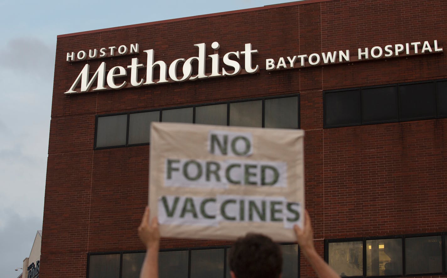 FILE - In this June 7, 2021, file photo, a person holds a sign to protest at Houston Methodist Hospital in Baytown, Texas, a policy that says hospital employees must get vaccinated against COVID-19 or lose their jobs. Over 150 employees at Houston Methodist system, who refused to get a COVID-19 vaccine, have been fired or resigned after a judge dismissed an employee lawsuit over the vaccine requirement, said Houston Methodist system spokesperson Gale Smith on Tuesday, June 22, 2021. (Yi-Chin Lee/Houston Chronicle via AP, File)