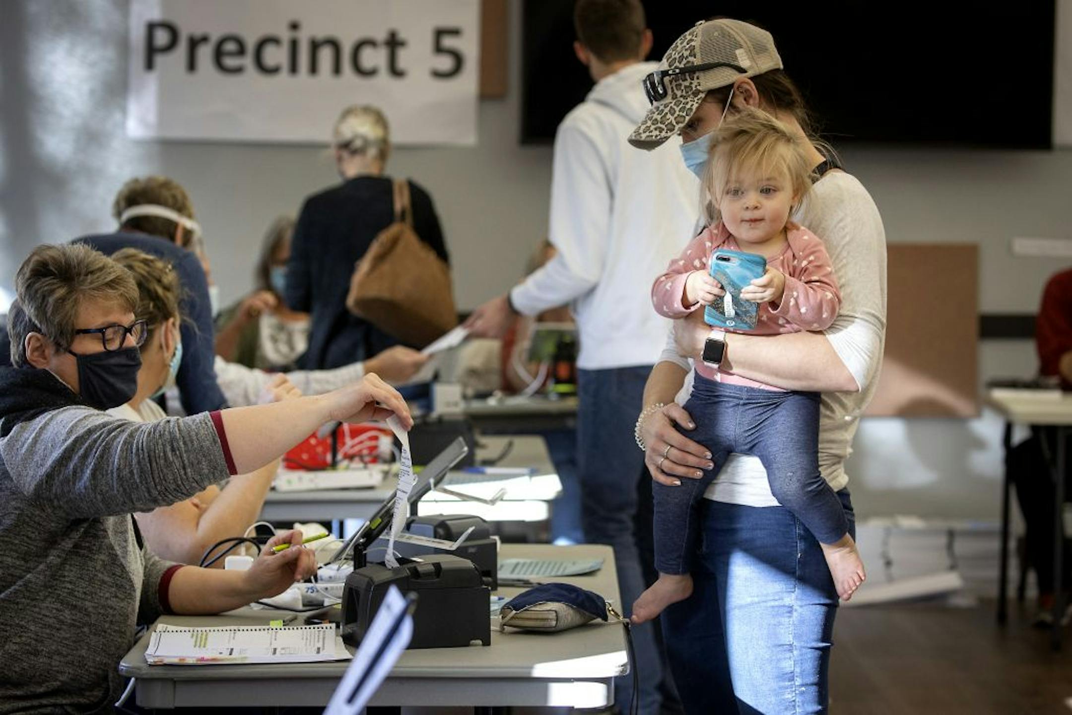 Kaitlin Miller, right, who said they waited for almost two hours, registered to vote with her daughter Raegahan, cq, in hand, at the Rambling River Center, Tuesday, November 3, 2020 in Farmington, MN.