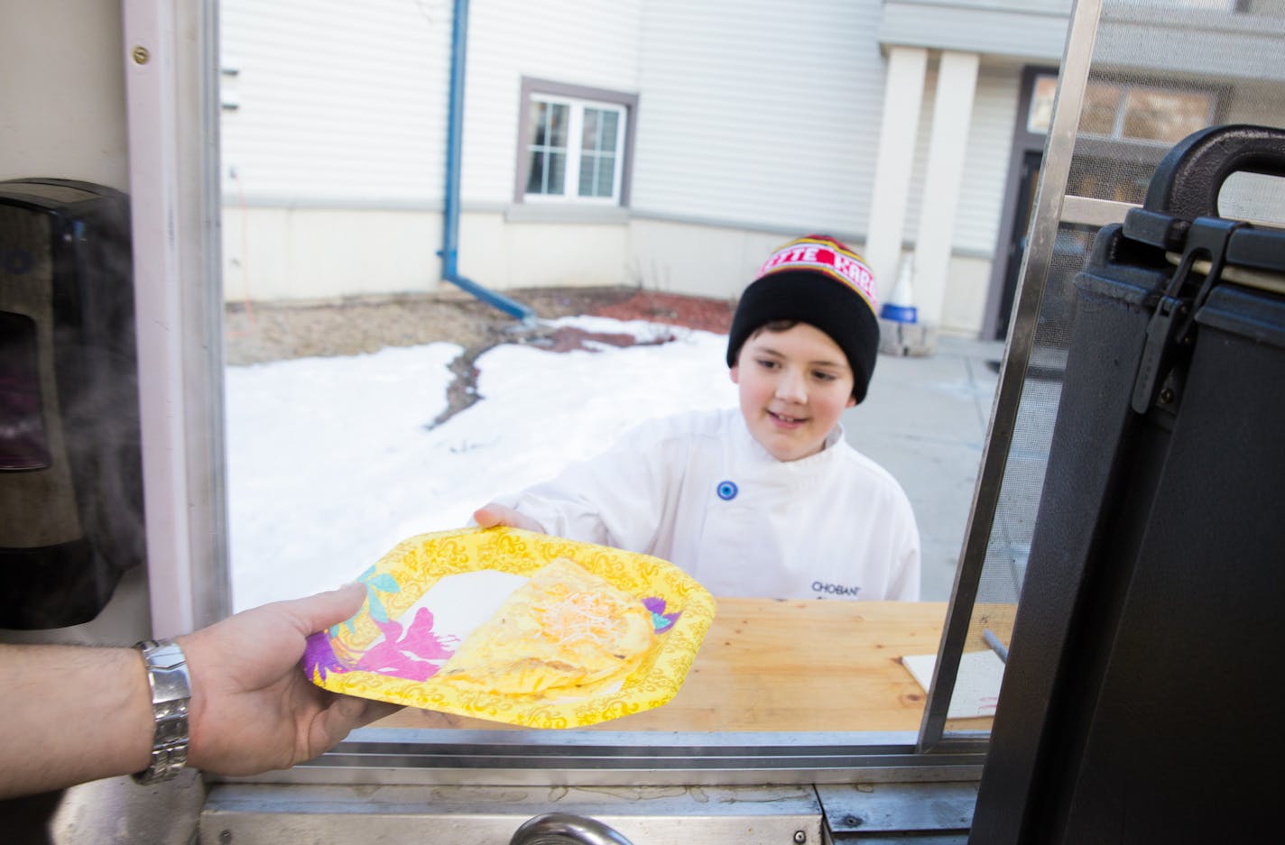 Lucas Hobbs, 13, Founder of Chef Lucas Food, recieves a freshly prepared omelette by Kabomelette, a food truck, to deliever to residents at the Dakota Woodlands Wednesday morning. ] Elizabeth Brumley special to the Star Tribune Intern. * Chef Lucas Foods foudned by Lucas Hobbs, 13, began after his Make-A-Wish to give away free food to people with a foodtruck.