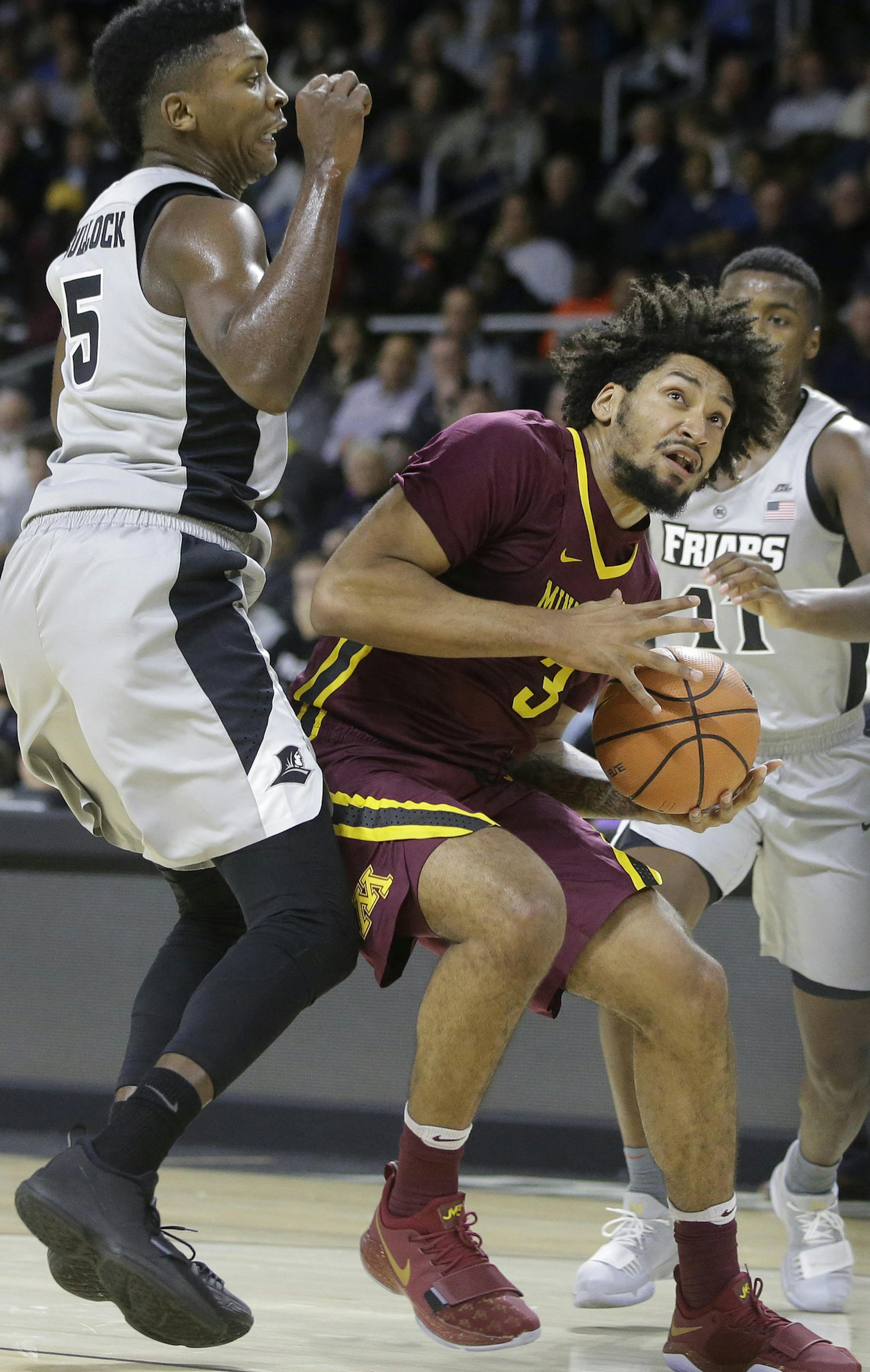 Minnesota's Jordan Murphy, center, looks for an opening past Providence's Rodney Bullock (5) and Alpha Diallo (11) in the first half of an NCAA college basketball game Monday, Nov. 13, 2017, in Providence, R.I. Minnesota won 86-74. (AP Photo/Steven Senne)