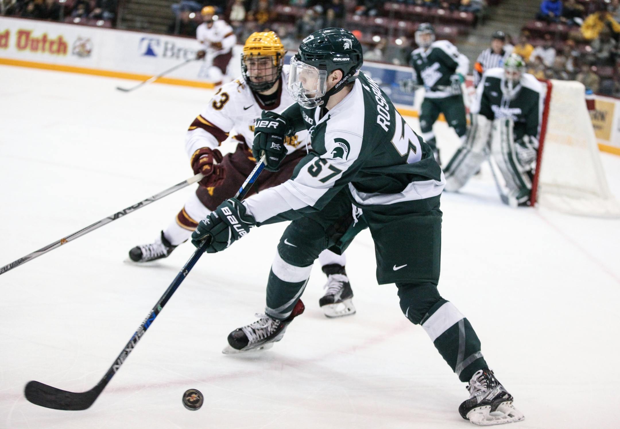 Minnesota Gophers� Ryan Norman (23) and Michigan State Spartans� Jerad Rosburg (57) chase the puck in the first period.