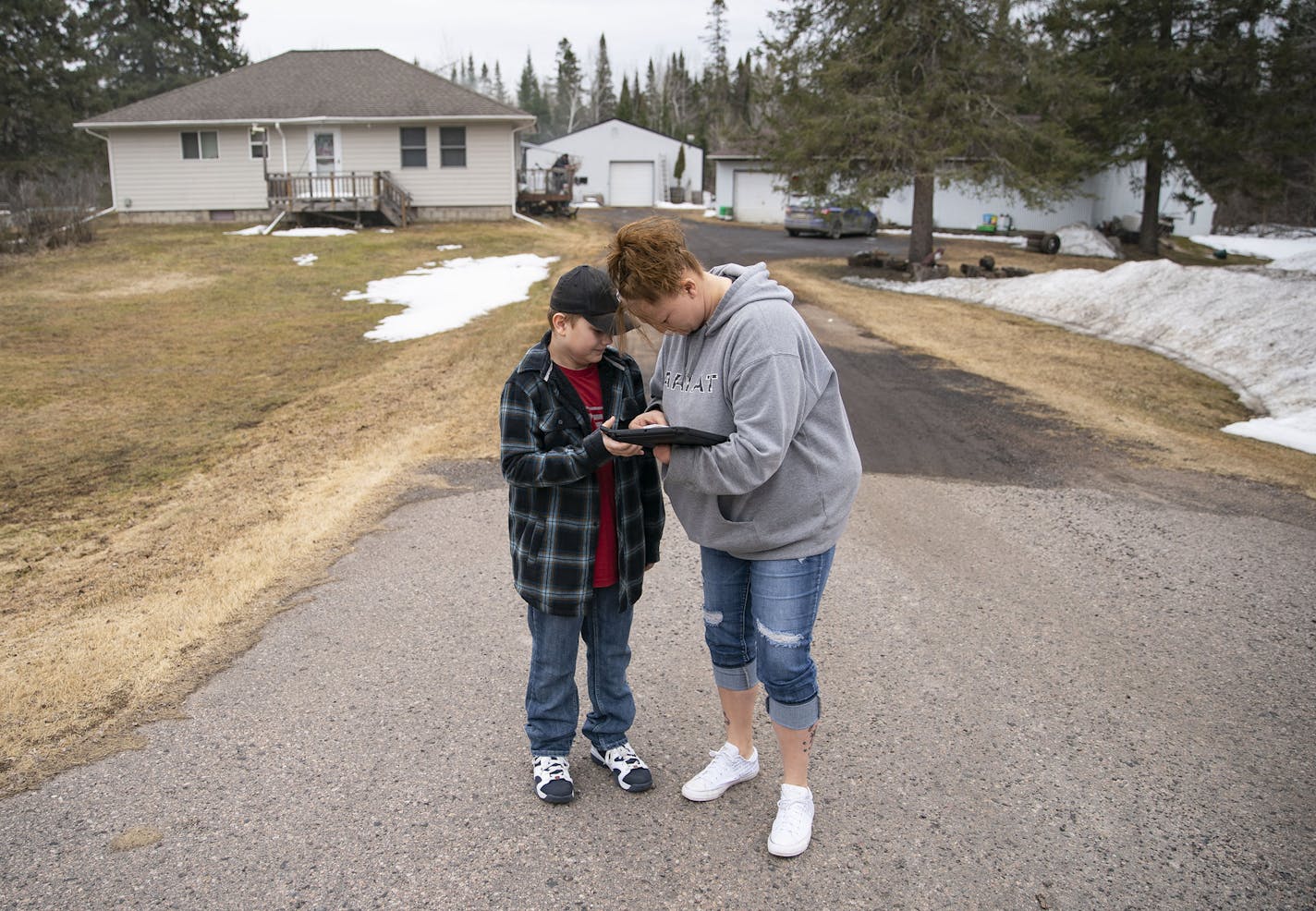 (Left) Michael Zakrajshek watched as his mom, Tawnya Heino, tried to connect to the internet at the end of their driveway in Chisholm, MN on Monday morning. They have to connect multiple times a day for zoom conferences with teachers and to download assignments for the day. They live only four miles outside of downtown, right on the highway but struggle to connect with the school provided hotspot. ] ALEX KORMANN • alex.kormann@startribune.com Broadband internet is a luxury that most Americans ta