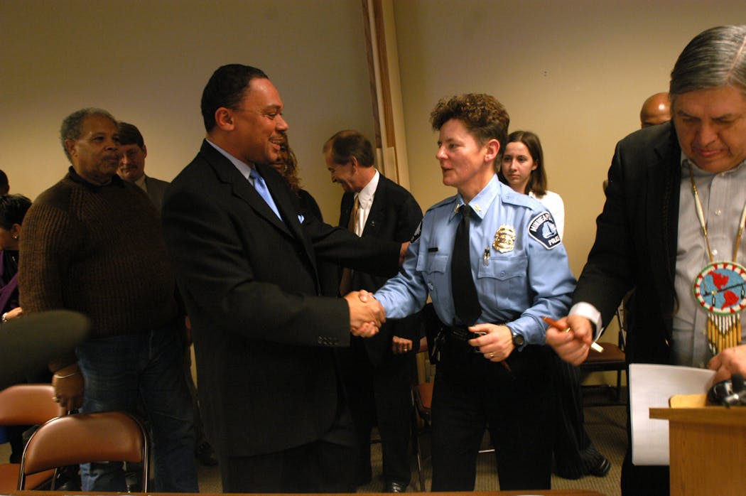 Rev. Ian Bethel shakes hands with Minneapolis police officer Sharon Lubinski after signing a federal mediation agreement between community and police at the Minneapolis Urban League on Dec. 4, 2003.