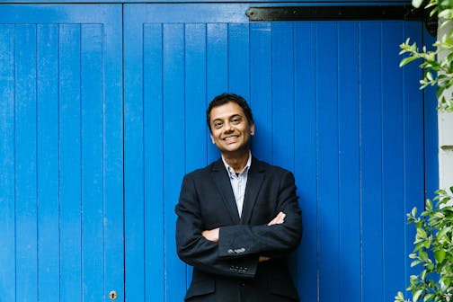 photo of author Neel Mukherjee in front of blue wall