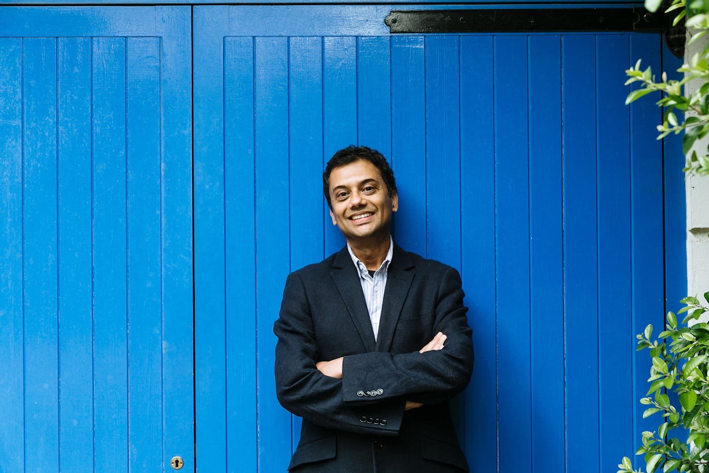 photo of author Neel Mukherjee in front of blue wall