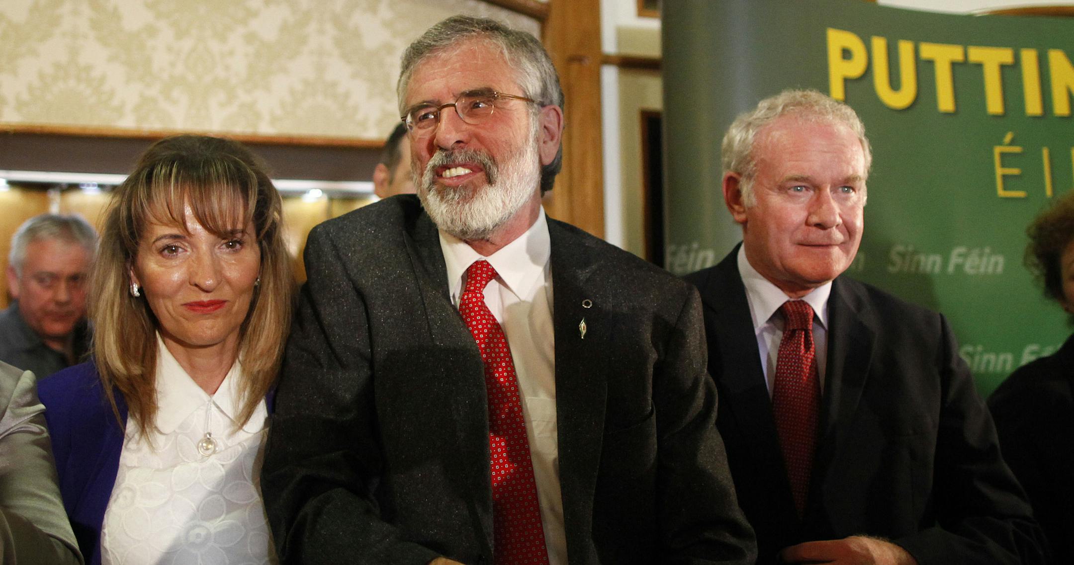 Sinn Fein President Gerry Adams, center, Martina Anderson, left, and Martin McGuinness speak to the media in West Belfast, Northern Ireland, Sunday May 4, 2014. Adams was released without charge Sunday after five days of police questioning over his alleged involvement in a decades-old Irish Republican Army killing, an event that has driven a dangerous wedge into Northern Ireland's unity government. (AP Photo/Peter Morrison)