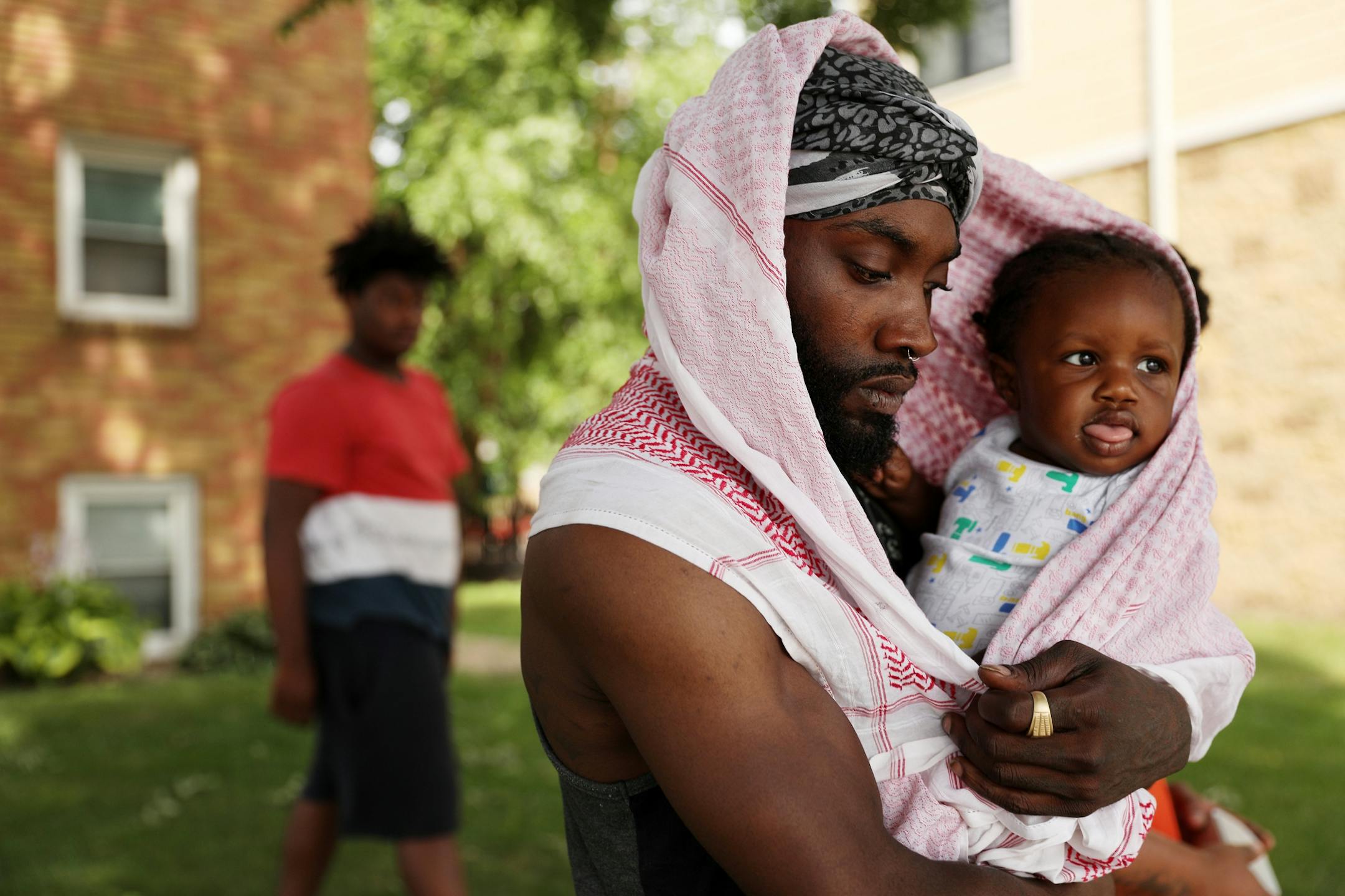 Jerome Peters Jr. held his son Jerome Peters III, as he walked from the apartment building where Thurman Blevins, who was killed by a Minneapolis police officer earlier in the week, lived after watching surveillance video of an attempted break in at Blevins' unit the previous night.