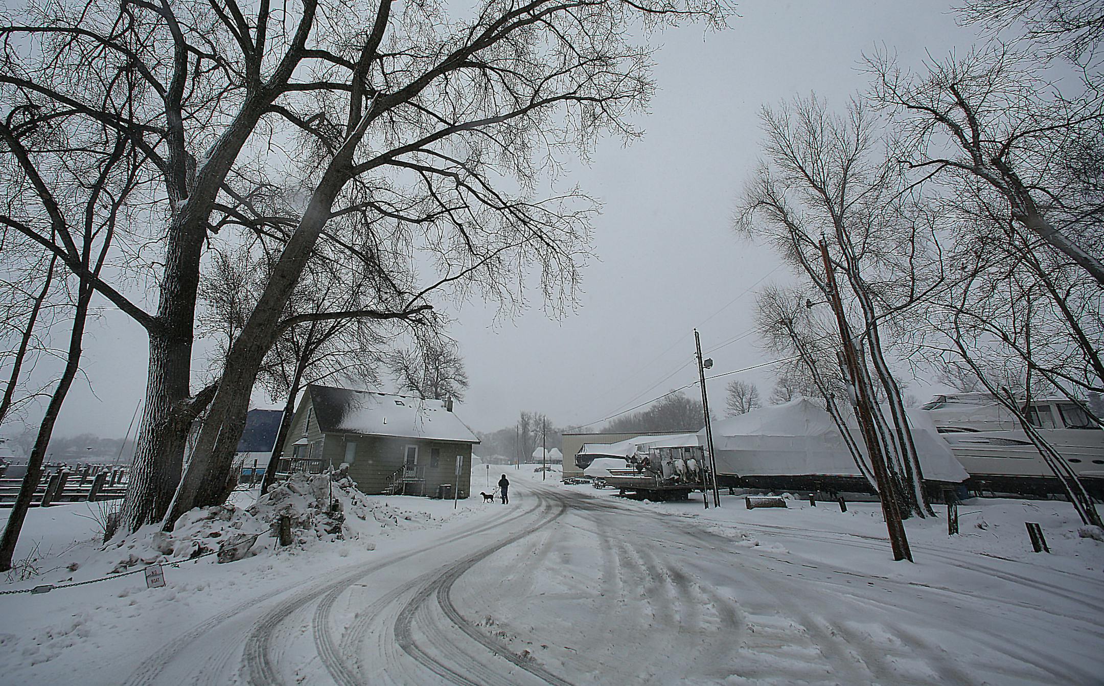 Snow fell atop docks and the shoreline at Tonka Bay Marina (facilities located on both sides of the road), where late-season ice on Lake Minnetonka has delayed many activities, including recreational boating, until warmer weather prevails. Last year the ice went out on the lake on March 21. This year several events have already been postponed, including the annual Lions Club crappie contest, which had been scheduled for this Saturday (April 20). ] (JIM GEHRZ/STAR TRIBUNE) / April 18, 2013 / 2:00