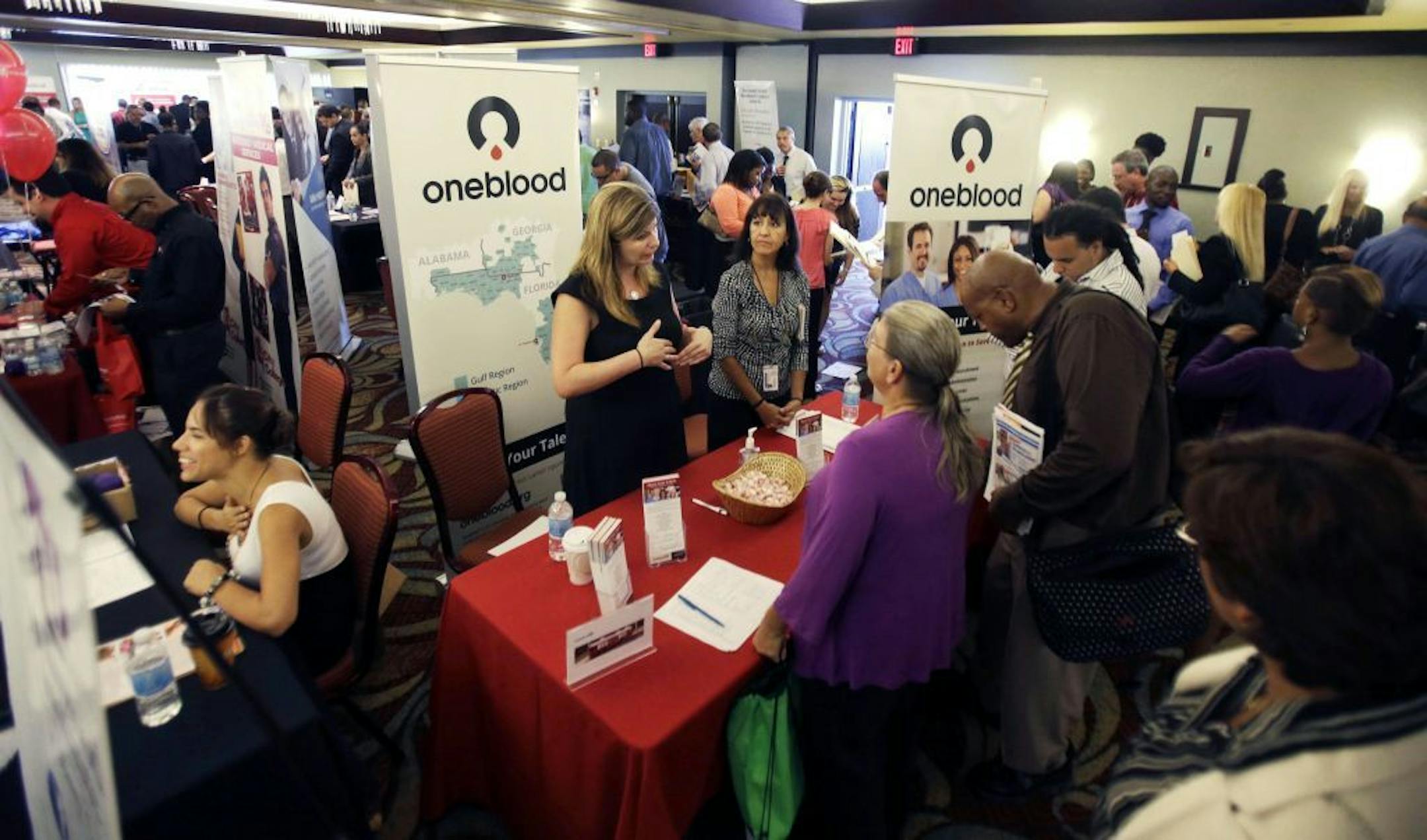 FILE - In this Aug. 14, 2013, file photo, people check out opportunities during a job fair in Miami Lakes, Fla.