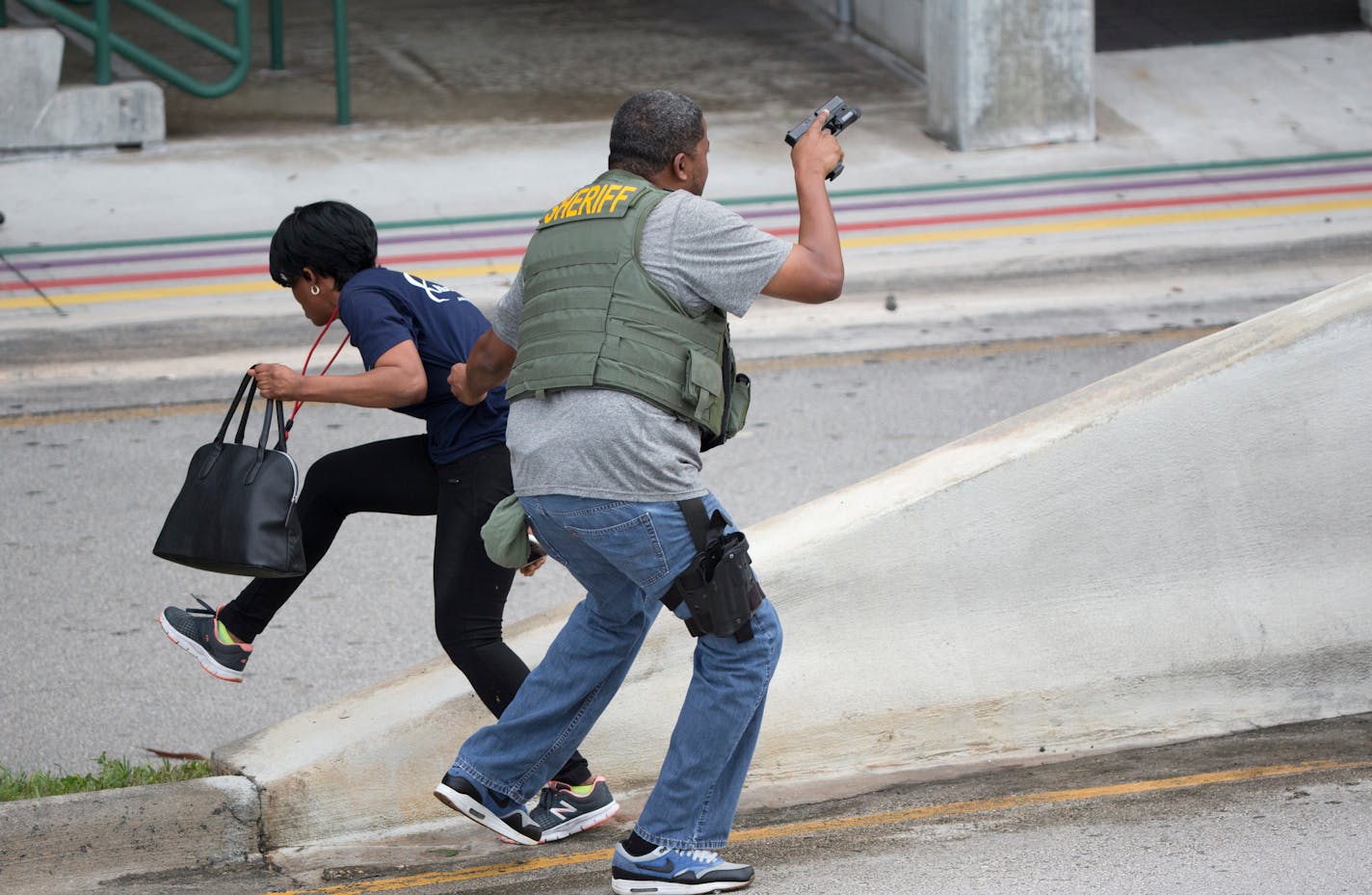 A law enforcement officer evacuates a civilian from an area at Fort Lauderdale-Hollywood International Airport, Friday, Jan. 6, 2017, in Fort Lauderdale, Fla. A gunman opened fire in the baggage claim area at the airport Friday, killing several people and wounding others before being taken into custody in an attack that sent panicked passengers running out of the terminal and onto the tarmac, authorities said. (AP Photo/Wilfredo Lee)