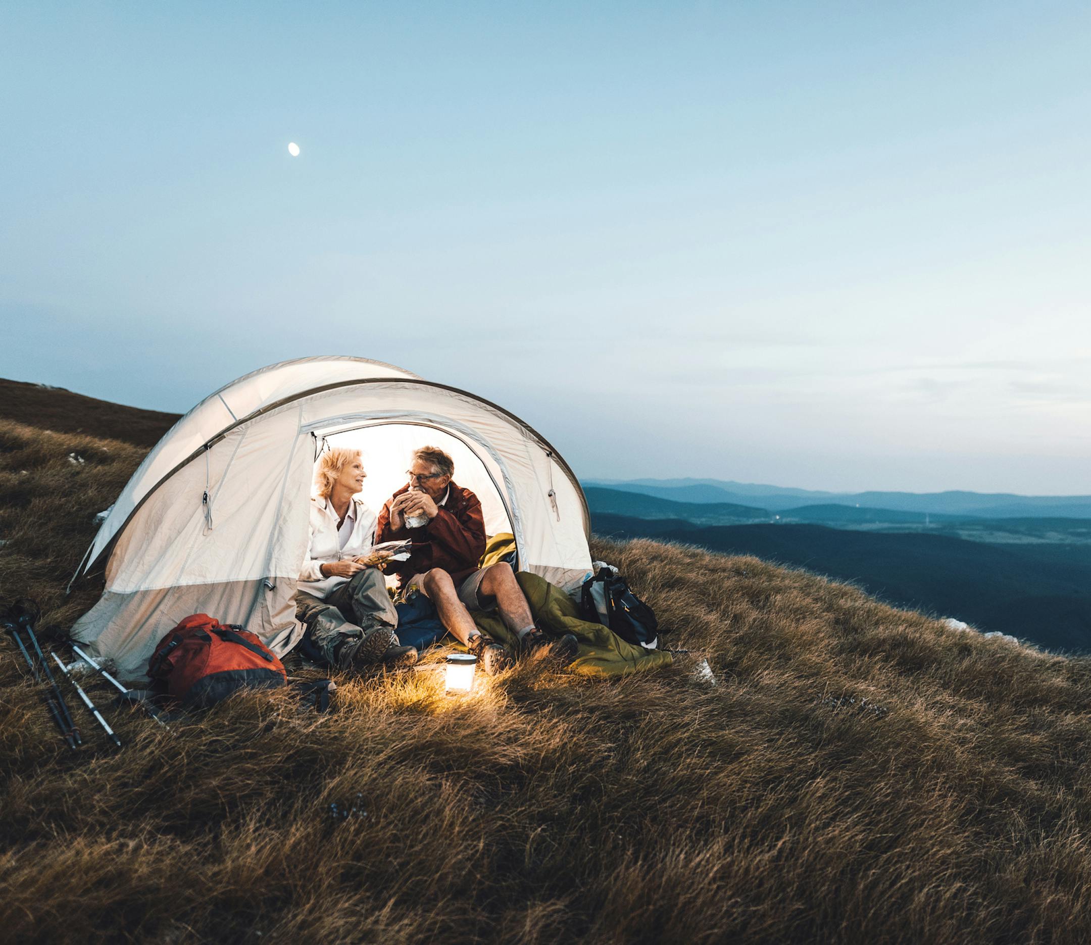 Senior couple camping in the mountains and eating a snack ORG XMIT: 775166672