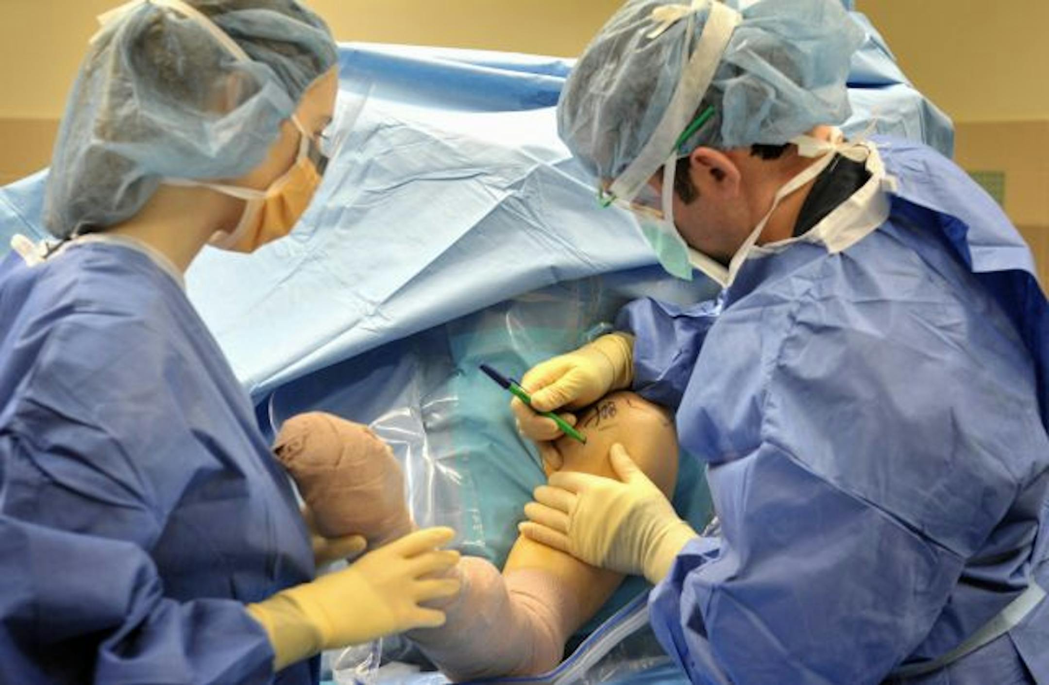 Dr. Jonathan Braman, right, assisted by resident Kate Pico, marked Jeffrey Scott for shoulder surgery Thursday at TRIA Orthopaedic Center in Bloomington.