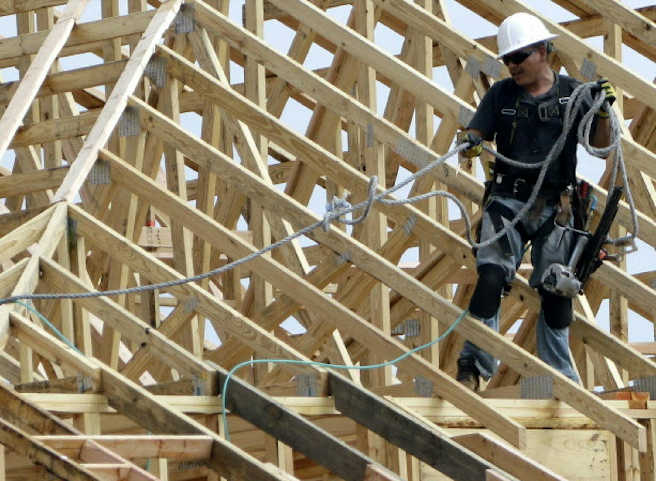 In this March 19, 2015 photo, a construction worker pulls his safety rope while working on the roof of an apartment complex being built in Spring, Texas. The Commerce Department releases fourth-quarter gross domestic product on Friday, March 27, 2015. (AP Photo/David J. Phillip)