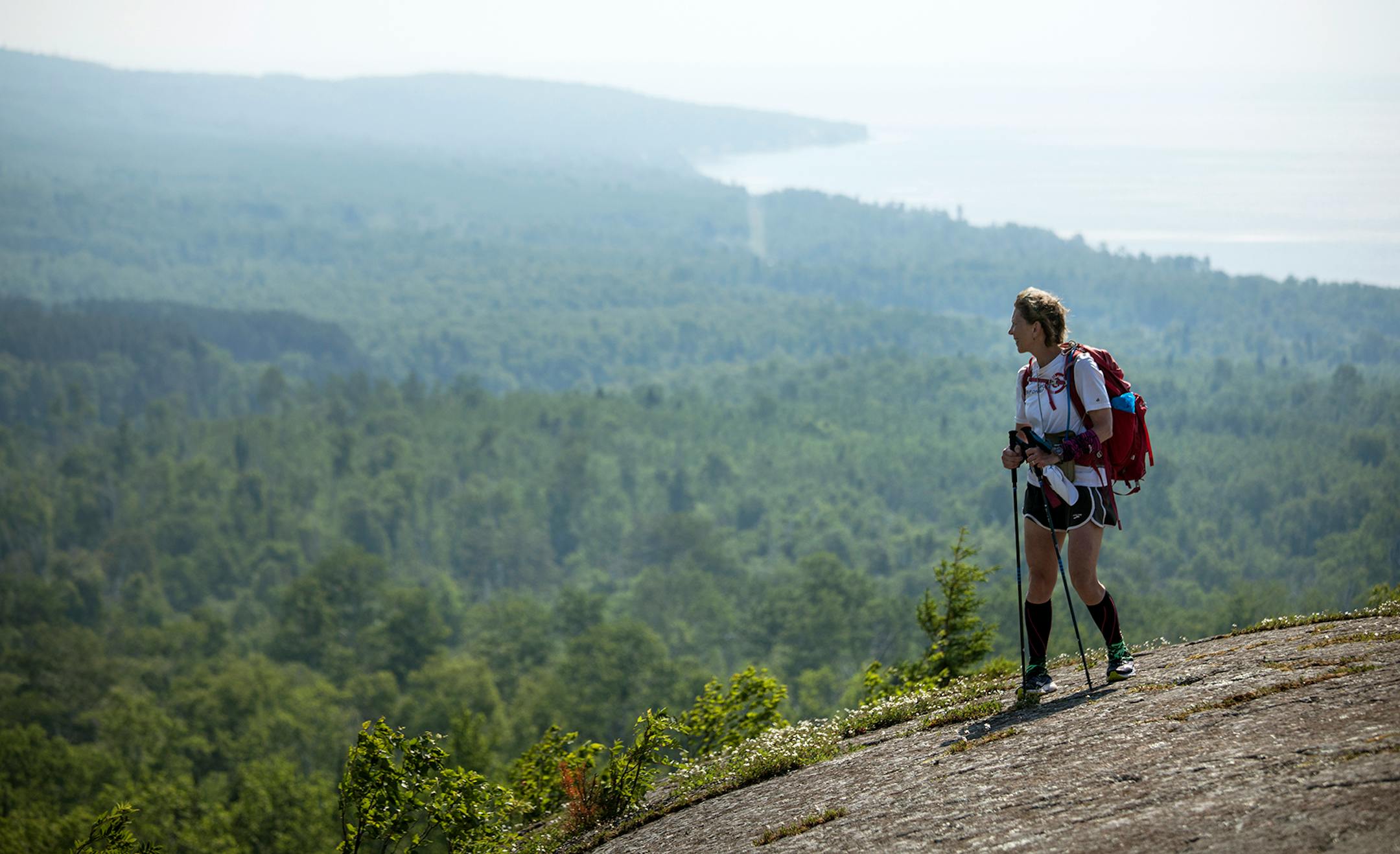 Day-17 - Melanie McManus hikes across the open rock face of Pincushion Mountain near Grand Marais. The outcrop rewards the hiker with spectacular views of Grand Marais, 5 mile rock in Lake Superior and the inland wilderness.] Grand Marais to Lake Walk
Superior Hiking Trail.
BRIAN PETERSON ¥ brian.peterson@startribune.com
Superior Hiking Trail, MN 06/18/2018