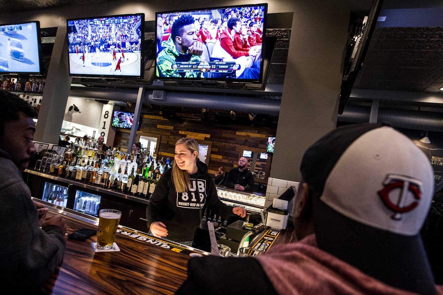 Melissa O'Brien serves customers as March Madness plays on the screens throughout Pub 819 in Hopkins March 22, 2015. (Courtney Perry)