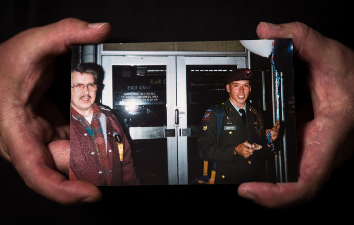 Chad Donovan held an old photo of himself standing next to his father during his days of military service.