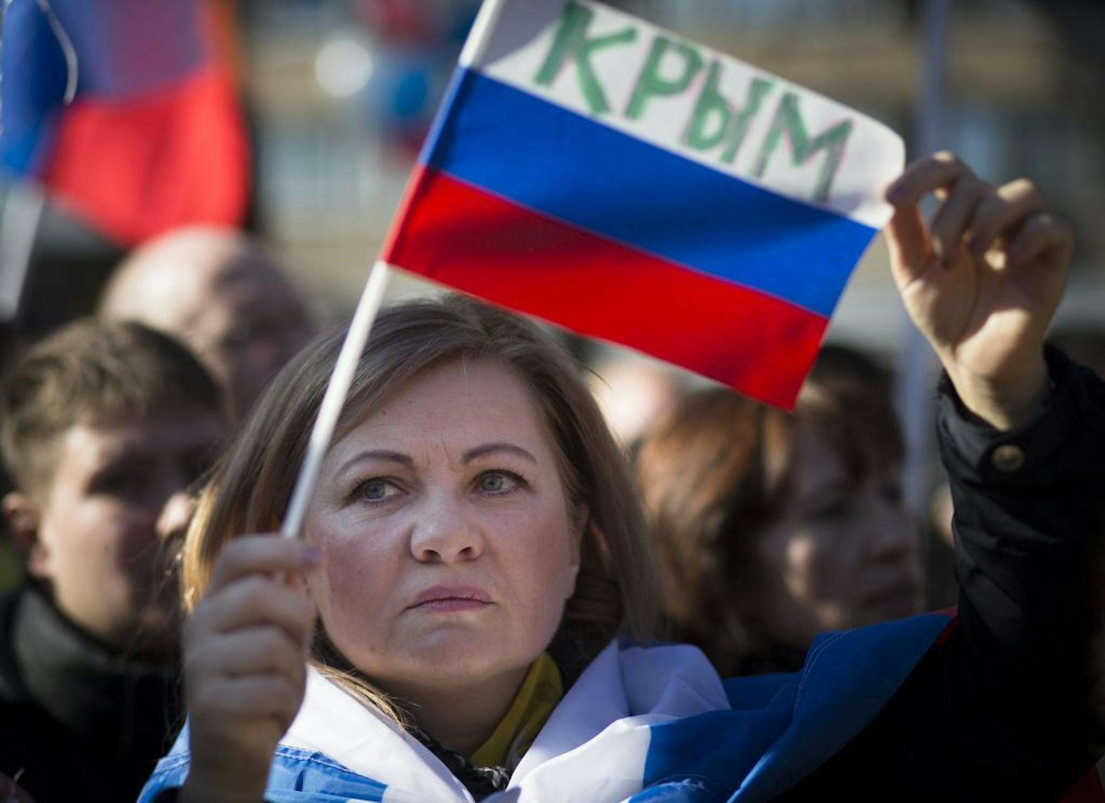 A woman holds a Russian flag with the word reading Crimea as about 1,000 demonstrators gathered to support Russians in Crimea in Moscow, Russia, Monday, March 10, 2014. Ukraine's Crimean peninsula, where a referendum has been called for Sunday on whether the region should split off and seek to become part of Russia.