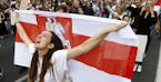 A woman reacts as she marches holding an old Belarusian national flag in the center of Minsk, Belarus, Friday, Aug. 14, 2020. Some thousands of people