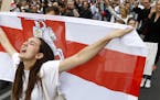 A woman reacts as she marches holding an old Belarusian national flag in the center of Minsk, Belarus, Friday, Aug. 14, 2020. Some thousands of people