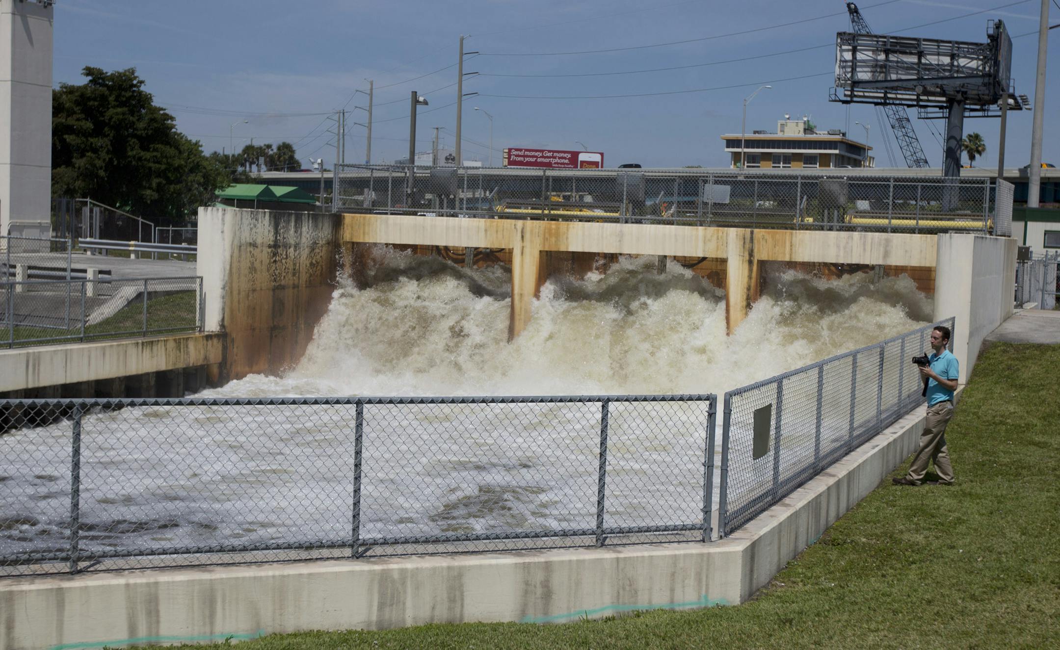 In this April 21, 2014 photo, a photographer watches as water is released back to the ocean in Miami. On Tuesday, April 22, 2014, members of the U.S. Senate are taking a field trip to Miami Beach for a hearing on the coastal effects of climate change. (AP Photo/J Pat Carter)