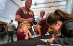 Alayna Sandbulte, 5, watched as Anne Miller signed her photo on the team roster. Her dad Craig stood behind her. The Gophers softball team has a rally