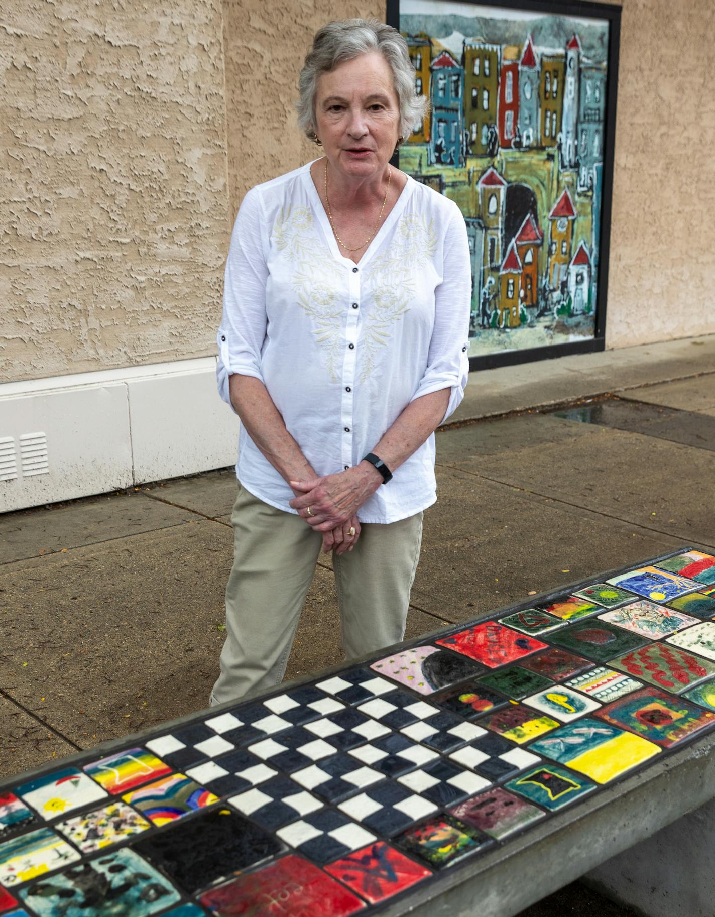 Janet Olney, executive director of the Willmar Area Arts Council, shows off one of eight benches that are being installed around Willmar as part of a public art project. Community members of all ages have painted about 600 tiles, which were fired in New London by potter Bill Gossman, who doubles as the town's mayor.