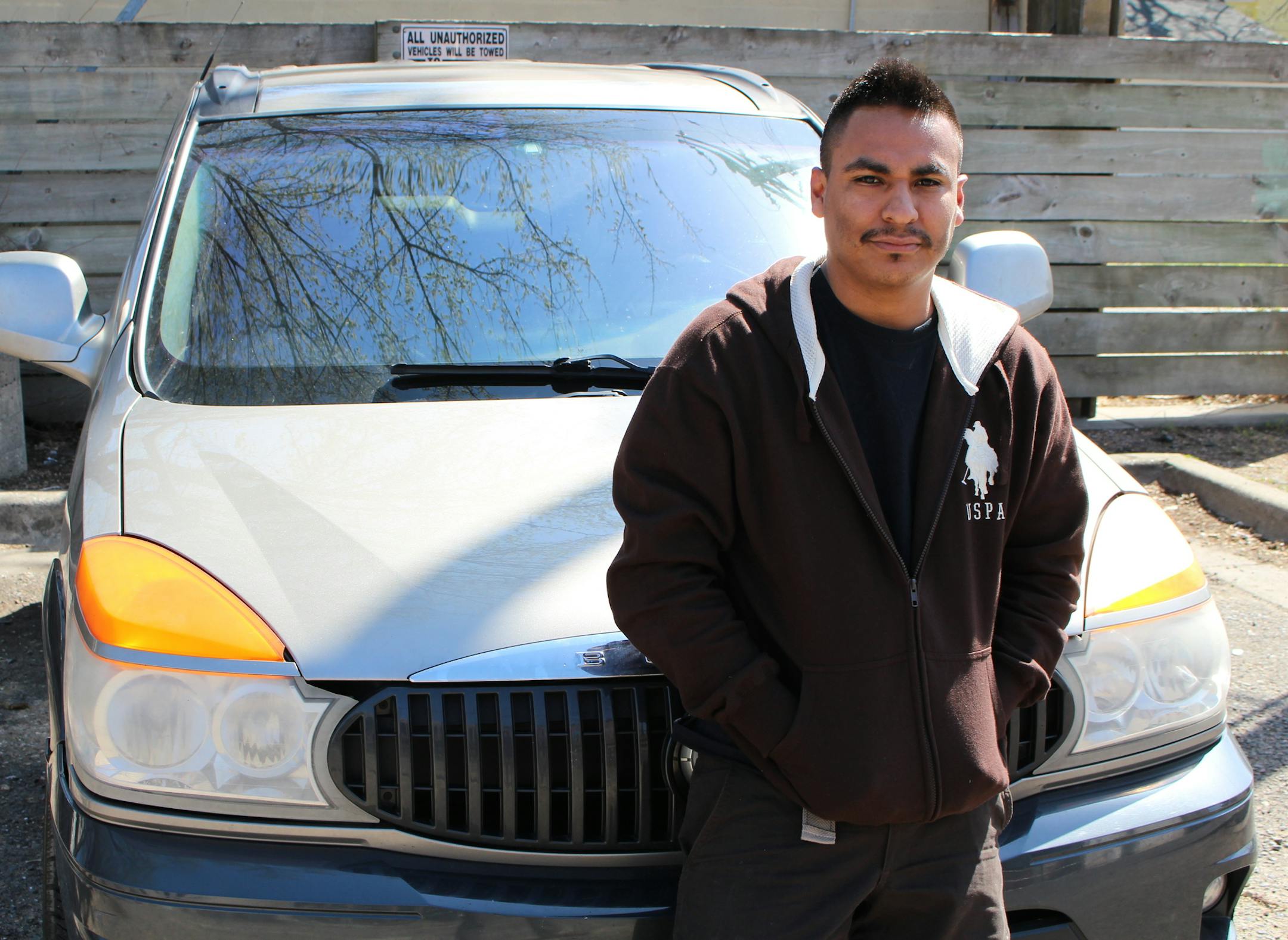Former tenant Miguel Flores stands outside the burnt building Thursday, leaning on a car where he now occassionaly sleeps.