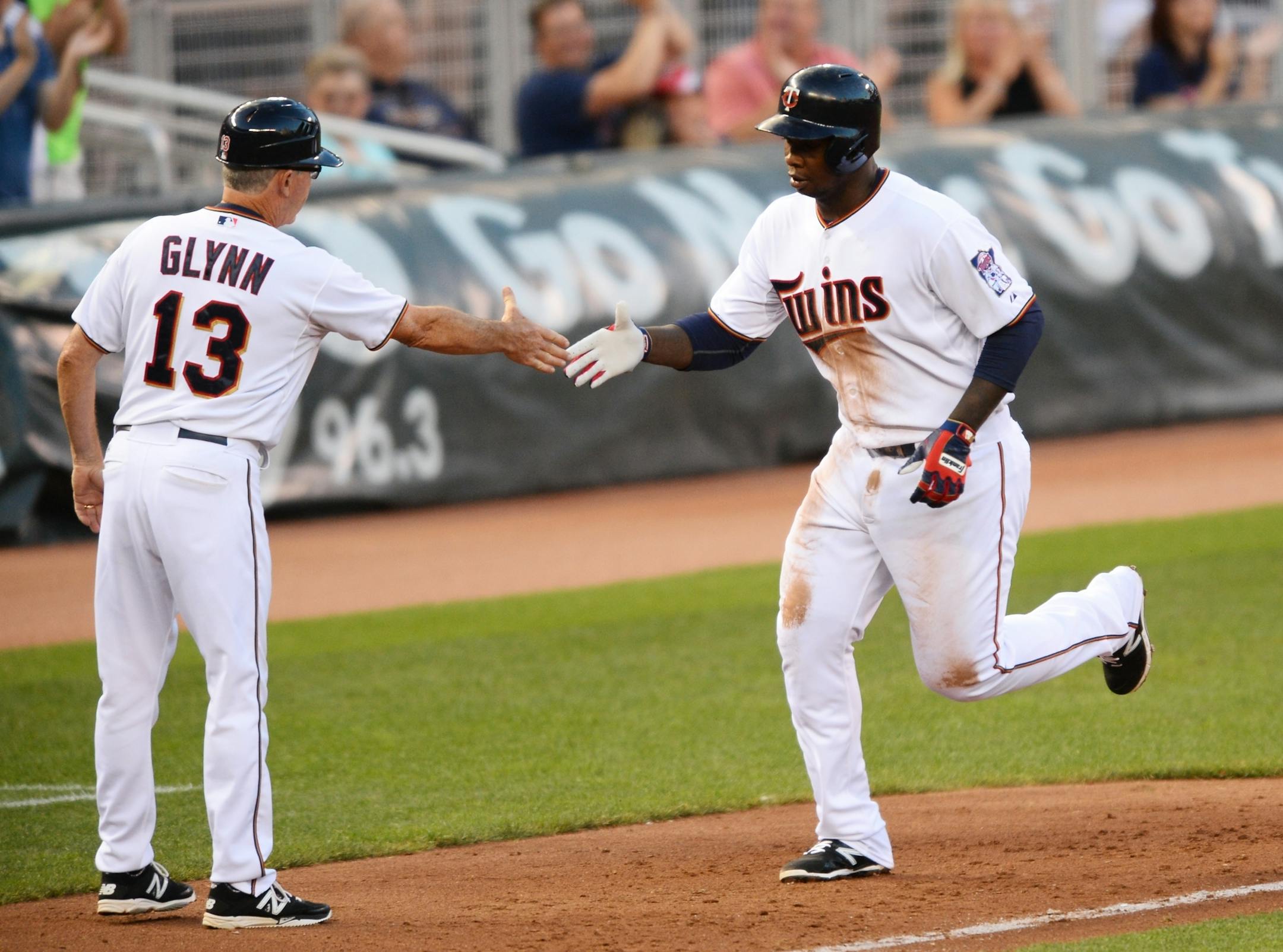 Sano and third base coach Gene Glynn celebrate a home run against Seattle.
