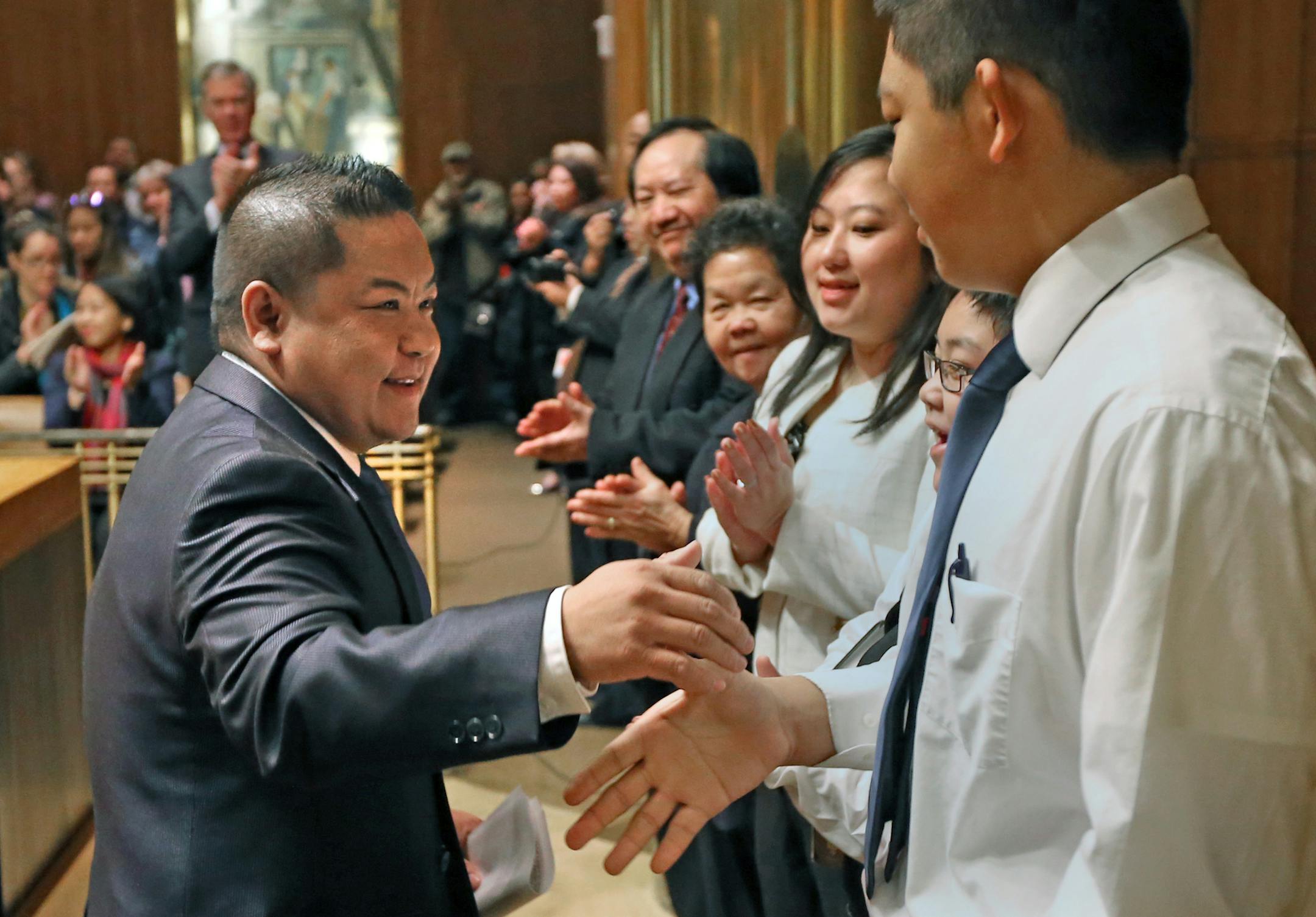 Dai Thao, left, the first Hmong-American to be elected to the St. Paul City Council, turned to hug his family, Mai Yang, Amee Xiong, Riley Thao (age-11) and Winston Thao (age-14) after he was sworn in, during a ceremony in the St. Paul City Hall on Thursday.