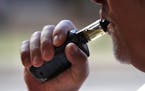 In this Aug. 28, 2019 photo a man smokes an e-cigarette in Portland, Maine. (AP Photo/Robert F. Bukaty) ORG XMIT: MER67b5446dd4796875b169998bcacdf
