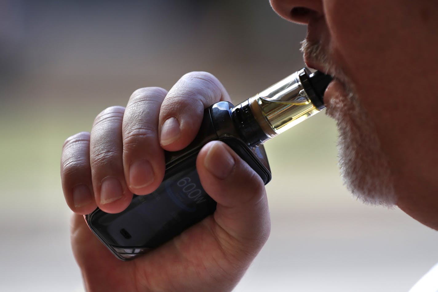 In this Aug. 28, 2019 photo a man smokes an e-cigarette in Portland, Maine. (AP Photo/Robert F. Bukaty) ORG XMIT: MER67b5446dd4796875b169998bcacdf