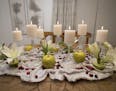 Jeralyn Mohr of Full Nest's holiday centerpiece includes apples, cranberries, limes, carrot tops, flowers and candles displayed on upside-down glasswa